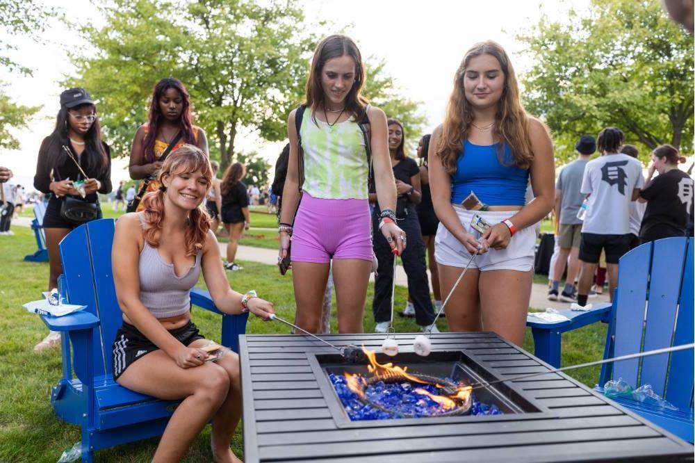 three students roasting marshmallows over a fire